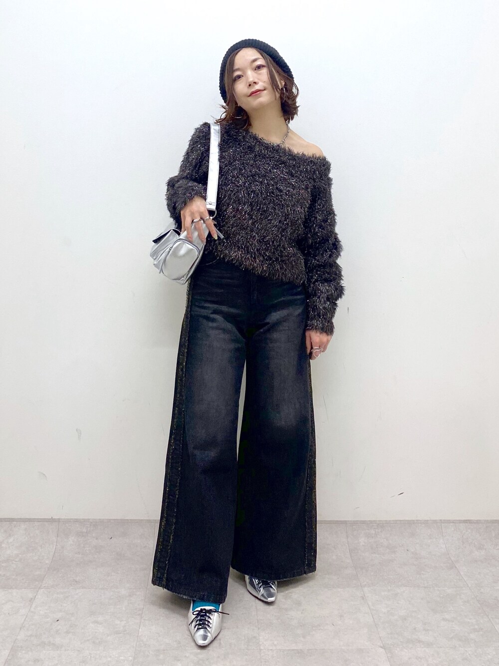 ブラック系のデニムパンツ、シルバー系のパンプス、シルバー系のショルダーバッグを着用したレディースの秋コーディネートの1枚目の写真