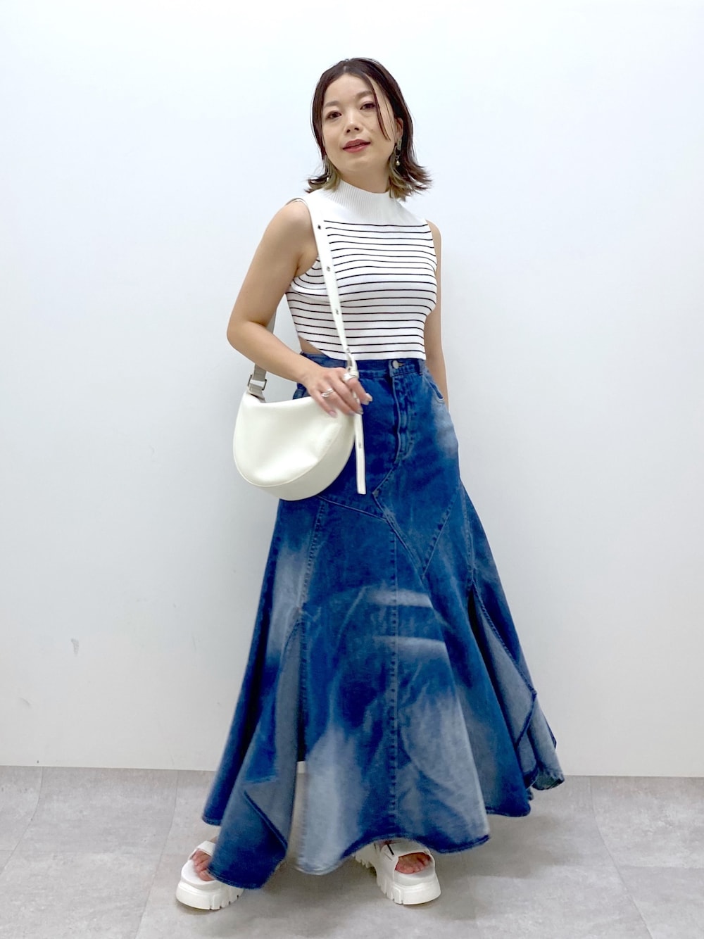 ホワイト系のショルダーバッグ、ブルー系のスカート、ホワイト系のTシャツ/カットソーを着用したレディースの夏コーディネートの1枚目の写真