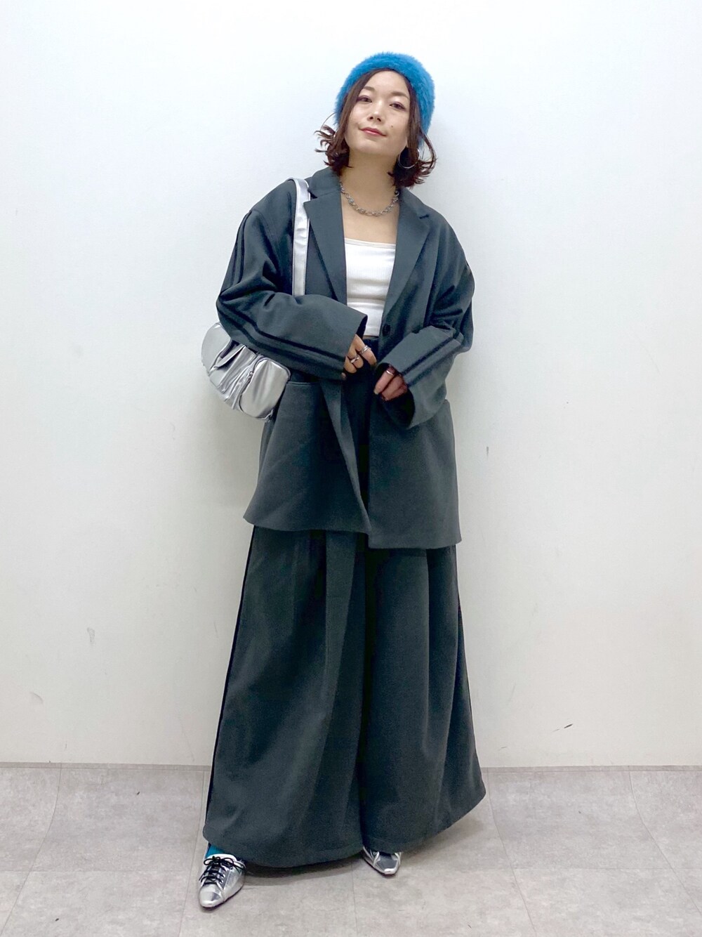 グレー系のスラックス、シルバー系のパンプス、シルバー系のショルダーバッグを着用したレディースの秋コーディネートの1枚目の写真