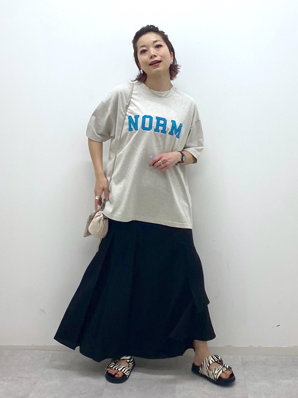 ベージュ系のTシャツ/カットソー、ブラック系のスカート、その他のサンダルを着用したレディースの夏コーディネートの1枚目の写真