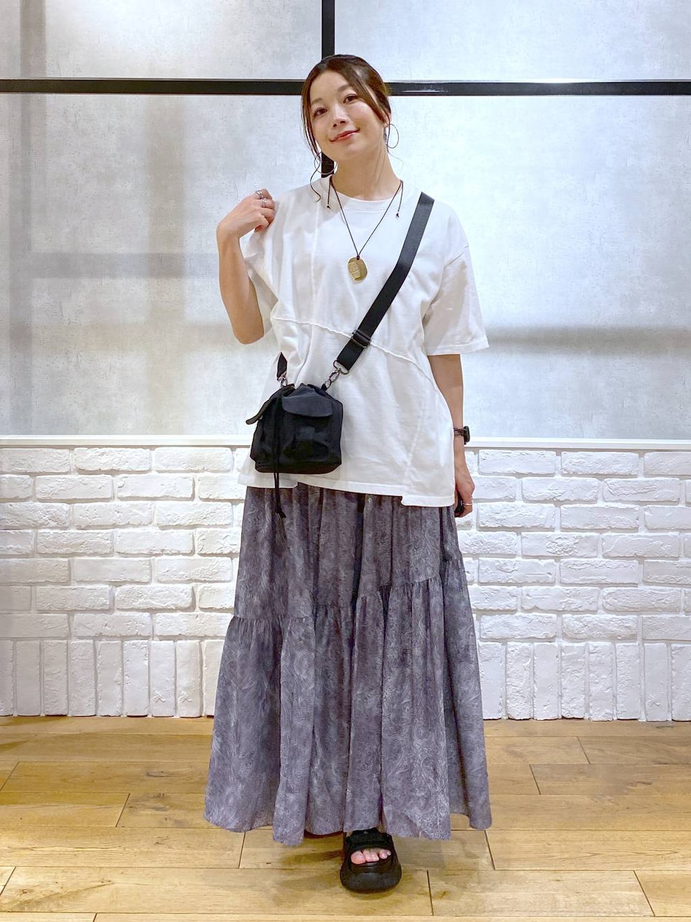 ブラック系のサンダル、ブラック系のショルダーバッグ、グレー系のスカートを着用したレディースの夏コーディネートの1枚目の写真