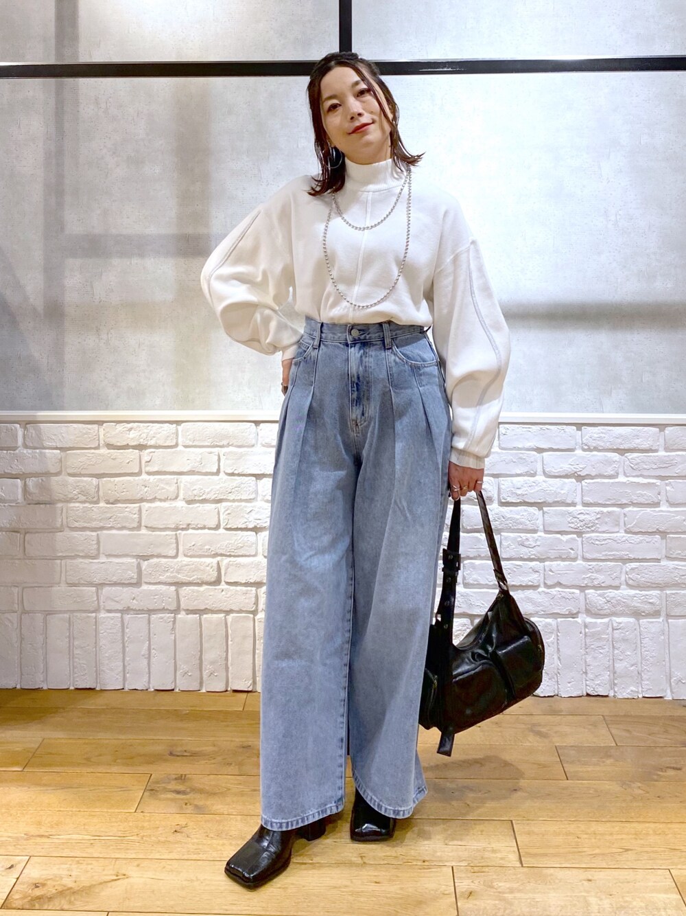 ホワイト系のニット/セーター、ブルー系のデニムパンツ、ブラック系のショルダーバッグを着用したレディースの冬コーディネートの1枚目の写真