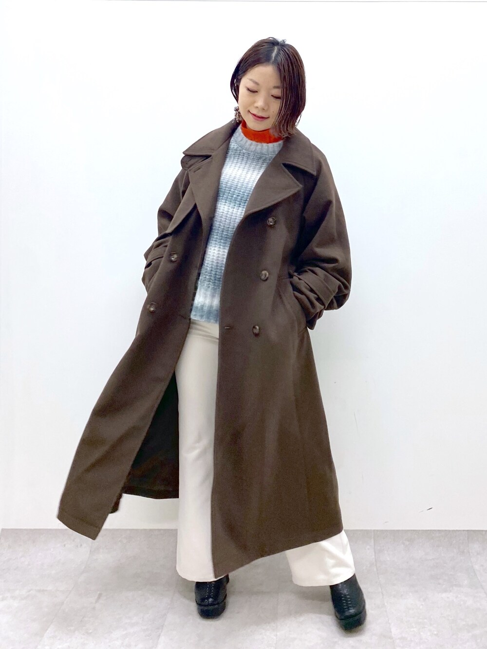 ブラック系のトップス、オレンジ系のトップス、ホワイト系のパンツを着用したレディースの秋コーディネートの1枚目の写真