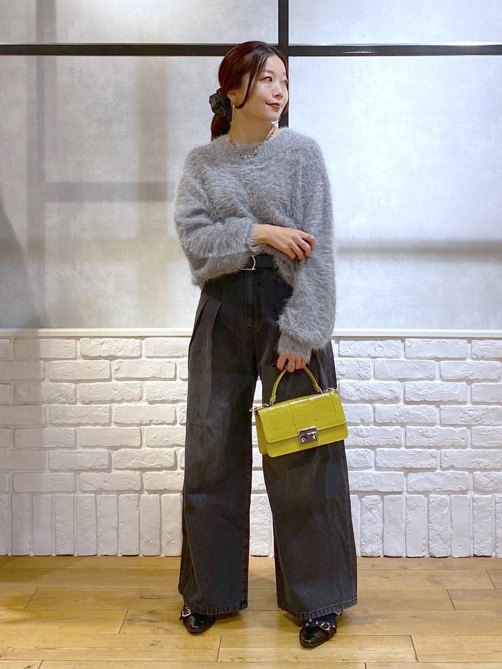 ブラック系のデニムパンツ、イエロー系のハンドバッグ、ブラック系のパンプスを着用したレディースの秋コーディネートの1枚目の写真