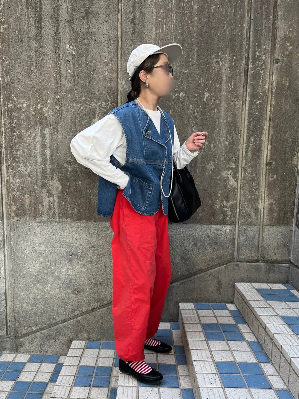 オレンジ系のその他パンツ、ブラック系のバレエシューズ、ブルー系のダウンベストを着用したレディースの春コーディネートの1枚目の写真