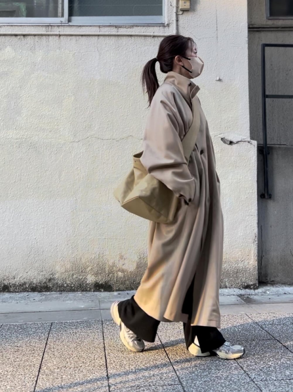 ベージュ系のステンカラーコート、ベージュ系のショルダーバッグ、ブラック系のその他パンツを着用したレディースの春コーディネートの1枚目の写真