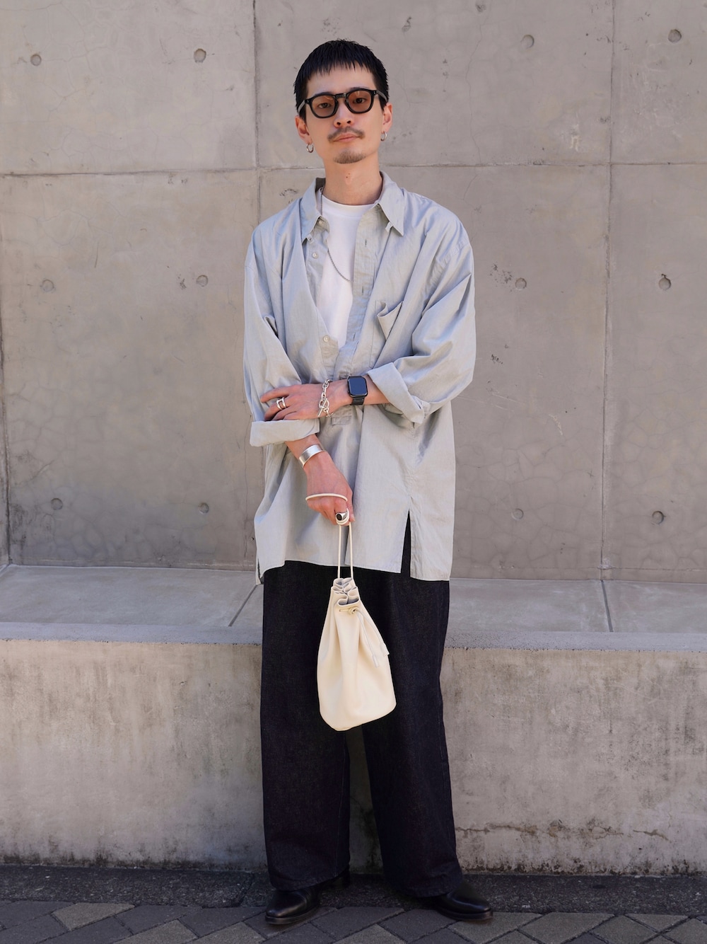 ホワイト系のショルダーバッグ、ブラック系のシューズ、ブルー系のデニムパンツを着用したメンズの秋コーディネートの1枚目の写真