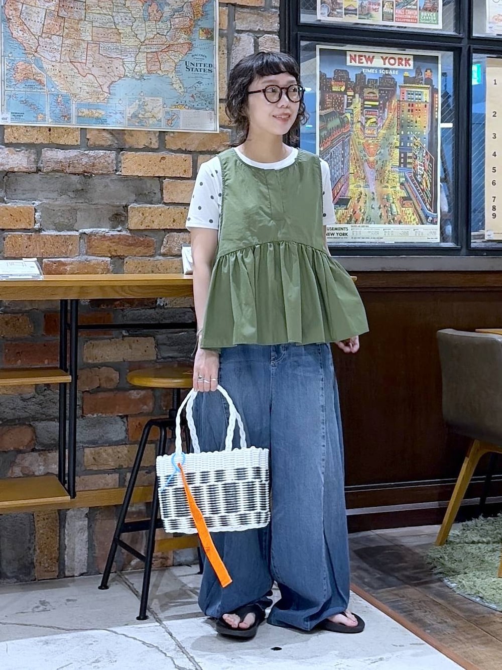 ブルー系のデニムパンツ、グリーン系のベスト、その他のかごバッグを着用したレディースの夏コーディネートの1枚目の写真