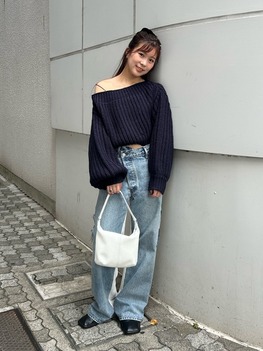 ブルー系のニット/セーター、ブルー系のデニムパンツ、ホワイト系のハンドバッグを着用したレディースの秋コーディネートの1枚目の写真