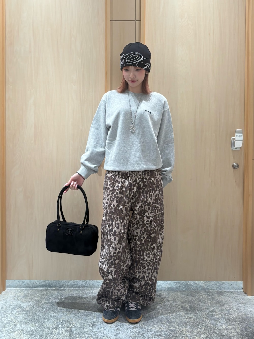 グレー系のスウェット、ベージュ系のカーゴパンツ、ブラック系のハンドバッグを着用したレディースの秋コーディネートの1枚目の写真