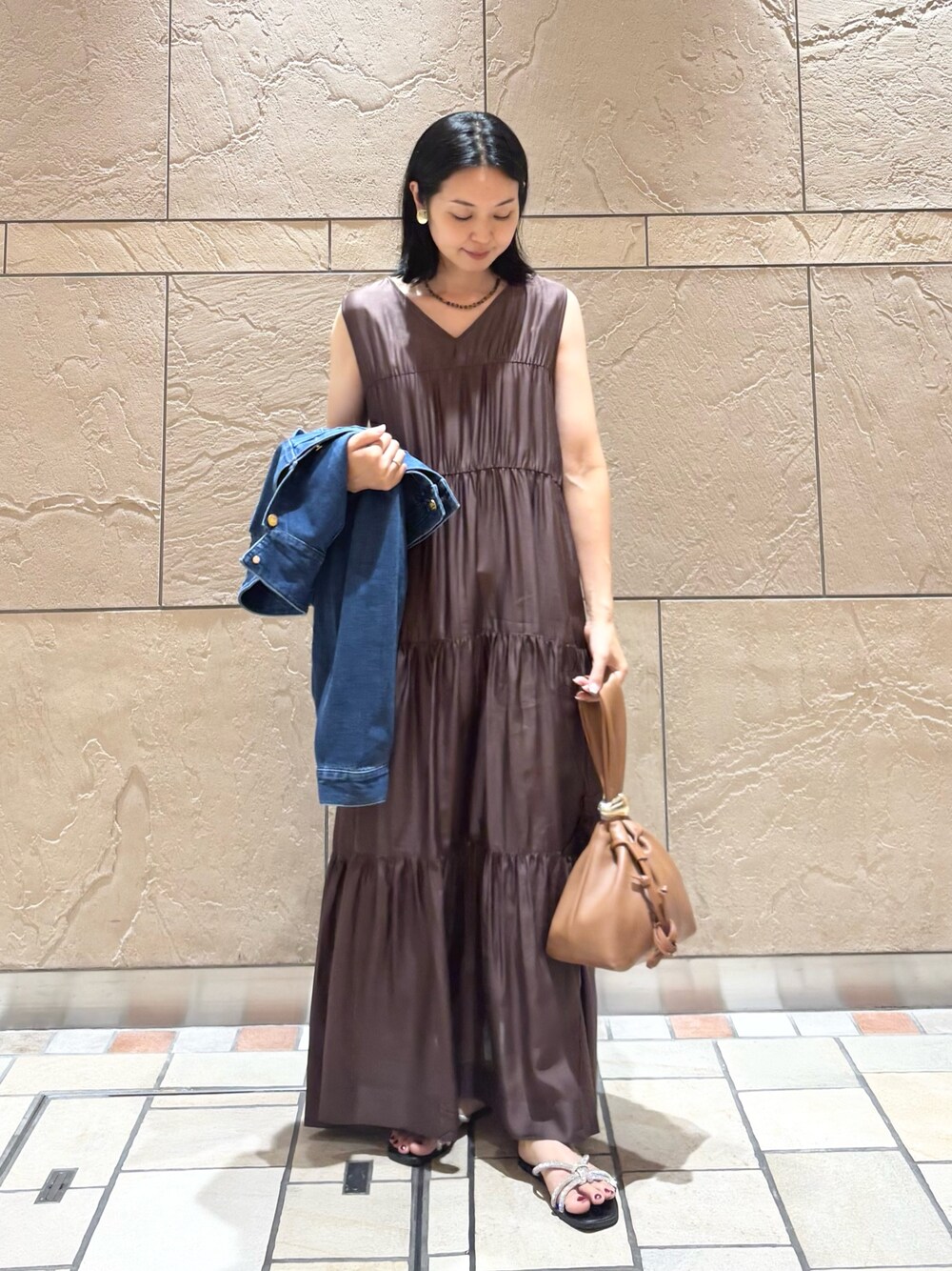 ブラウン系のワンピース、ブラウン系のバッグ、ブルー系のデニムジャケットを着用したレディースの夏コーディネートの1枚目の写真