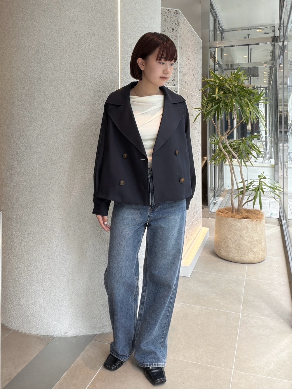 ブルー系のトレンチコート、ホワイト系のTシャツ/カットソー、ブルー系のデニムパンツを着用したレディースの秋コーディネートの1枚目の写真