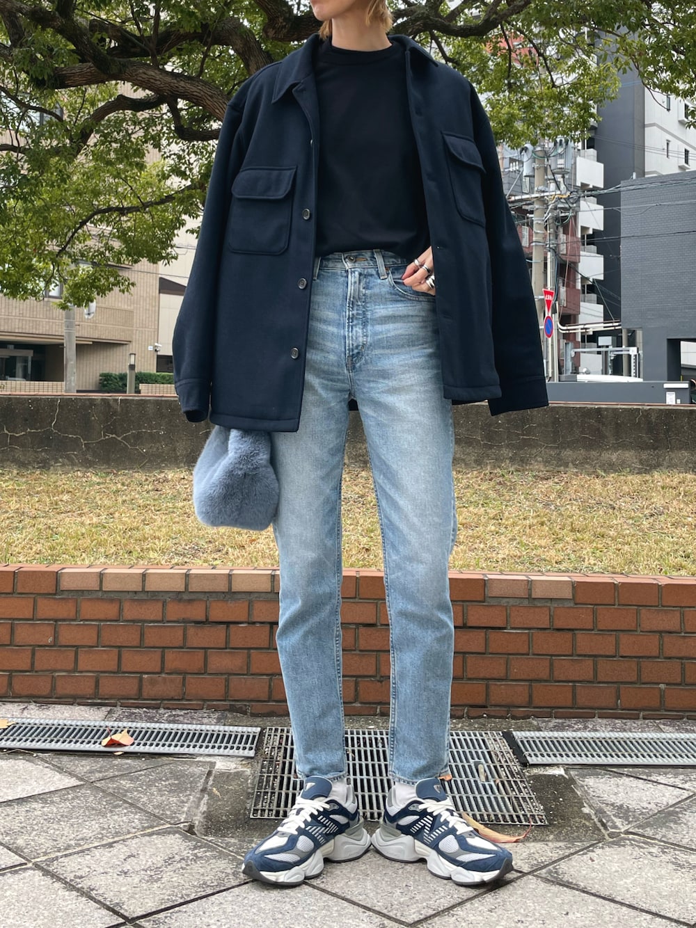 ブルー系のハンドバッグ、ブルー系のデニムパンツ、ブルー系のスニーカーを着用したレディースの冬コーディネートの1枚目の写真