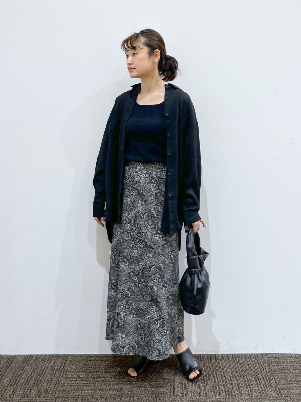 ブラック系のスカート、ブラック系のショルダーバッグ、ブラック系のシャツ/ブラウスを着用したレディースの春コーディネートの2枚目の写真