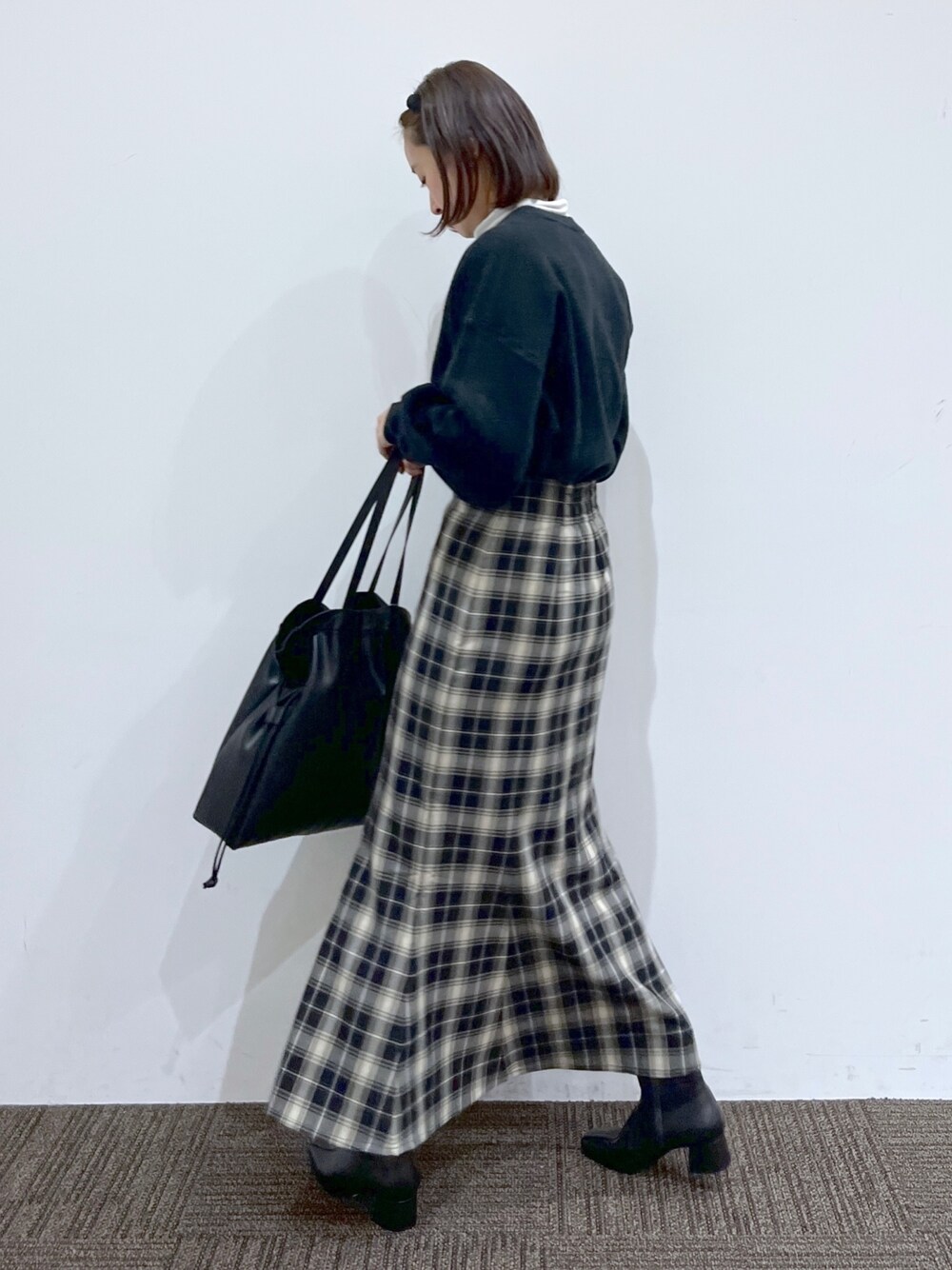 ブラック系のスカート、ホワイト系のTシャツ/カットソー、ブラック系のニット/セーターを着用したレディースの冬コーディネートの3枚目の写真