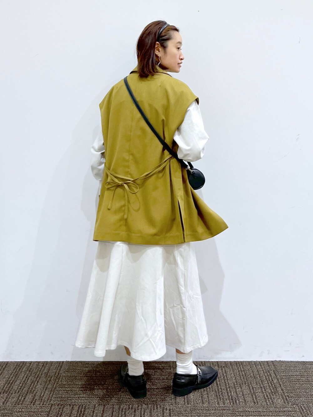 イエロー系のジャケット/アウター、ブラック系のショルダーバッグ、ホワイト系のワンピース/ドレスを着用したレディースの春コーディネートの3枚目の写真