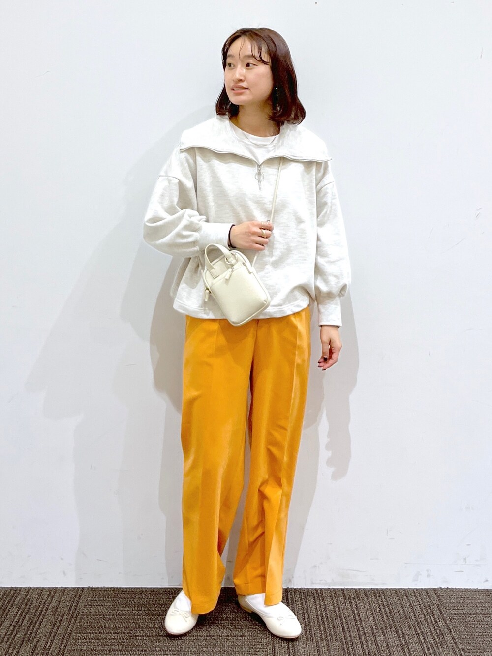 ホワイト系のバレエシューズ、オレンジ系のその他パンツ、ホワイト系のショルダーバッグを着用したレディースの冬コーディネートの1枚目の写真