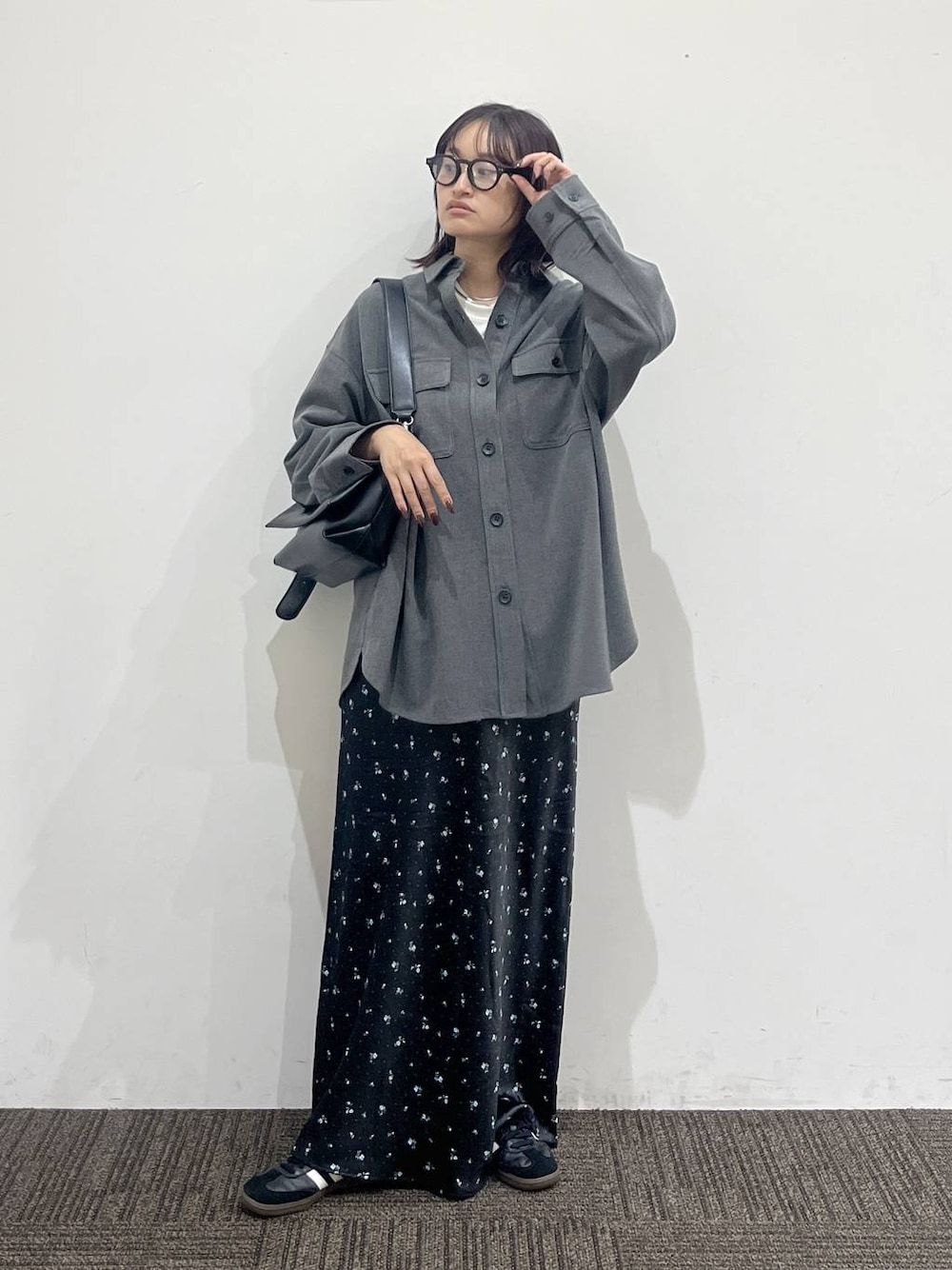 ブラック系のショルダーバッグ、ホワイト系のTシャツ/カットソー、ブラック系のスカートを着用したレディースの秋コーディネートの1枚目の写真