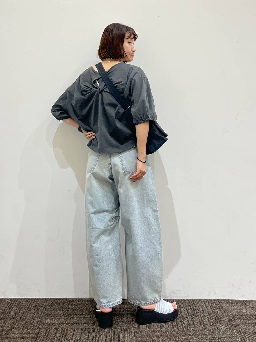 シルバー系のサンダル、ブラック系のショルダーバッグ、ブルー系のデニムパンツを着用したレディースの夏コーディネートの1枚目の写真