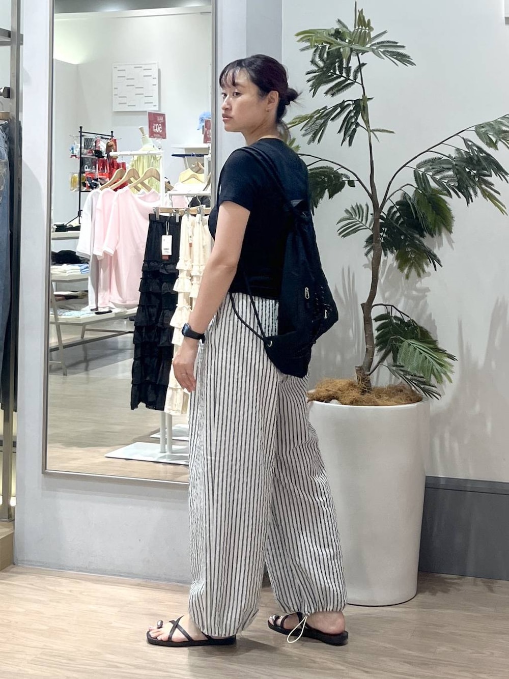 ブラック系のTシャツ/カットソー、ブラック系のサンダル、ブラック系のバックパック/リュックを着用したレディースの夏コーディネートの1枚目の写真
