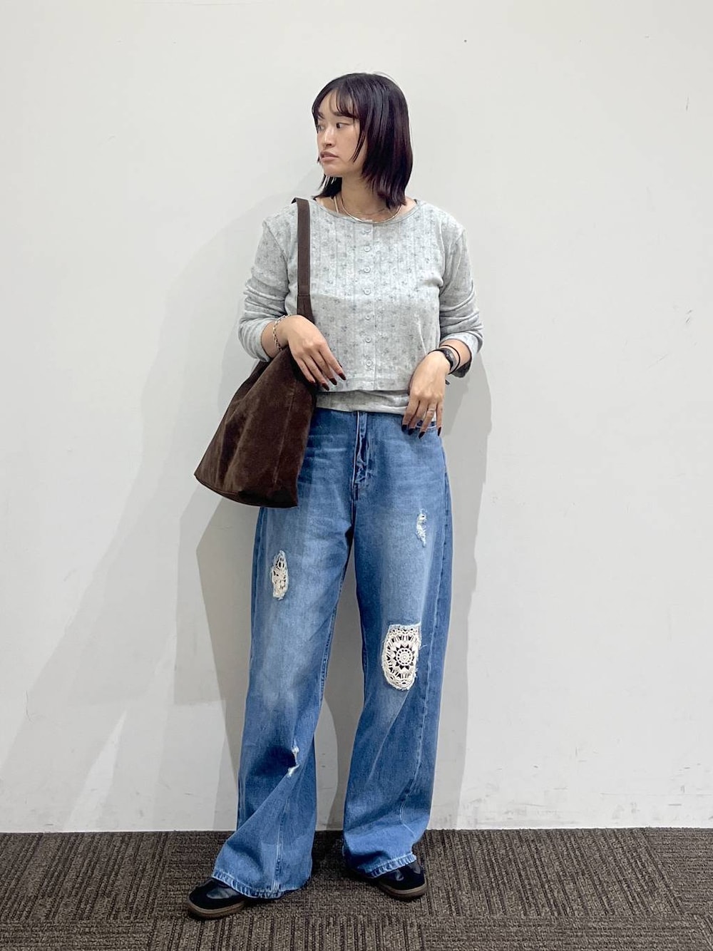 グレー系のTシャツ/カットソー、ブラウン系のショルダーバッグ、ブルー系のデニムパンツを着用したレディースの秋コーディネートの1枚目の写真