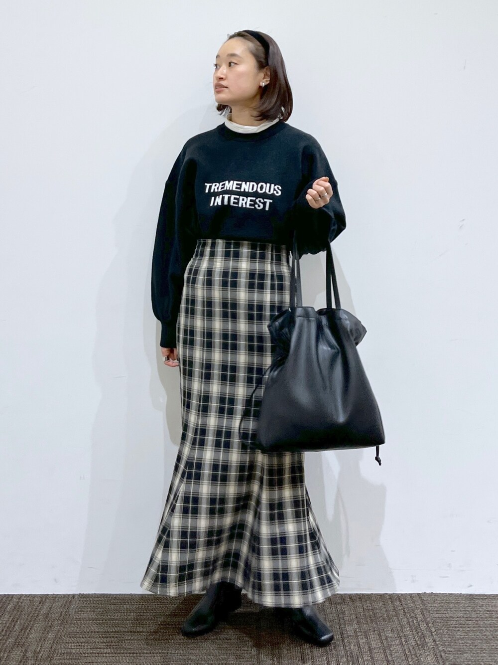 ブラック系のスカート、ホワイト系のTシャツ/カットソー、ブラック系のニット/セーターを着用したレディースの冬コーディネートの2枚目の写真