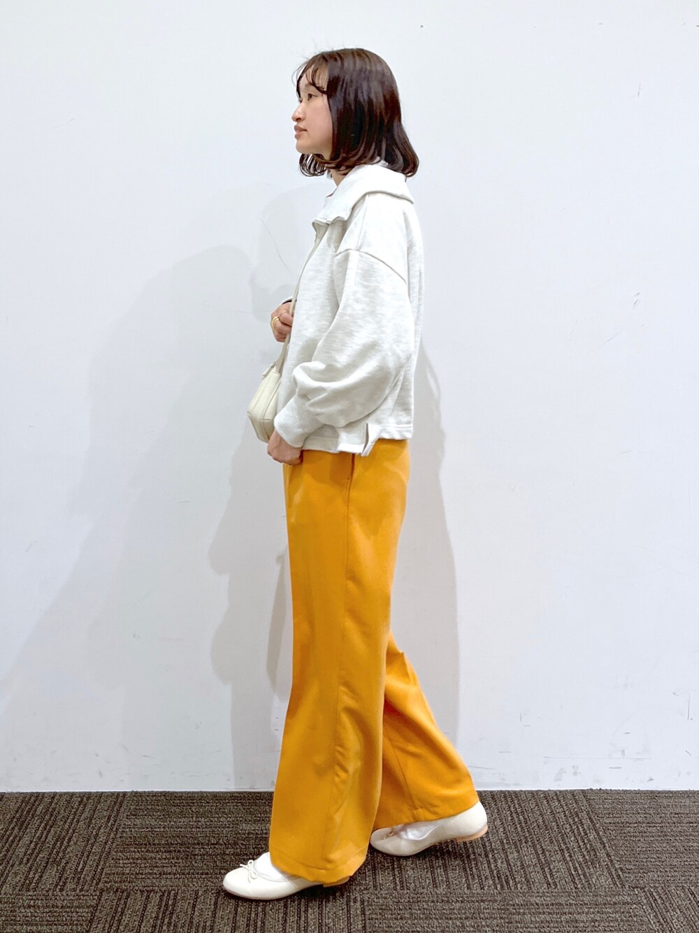 ホワイト系のバレエシューズ、オレンジ系のその他パンツ、ホワイト系のショルダーバッグを着用したレディースの冬コーディネートの2枚目の写真