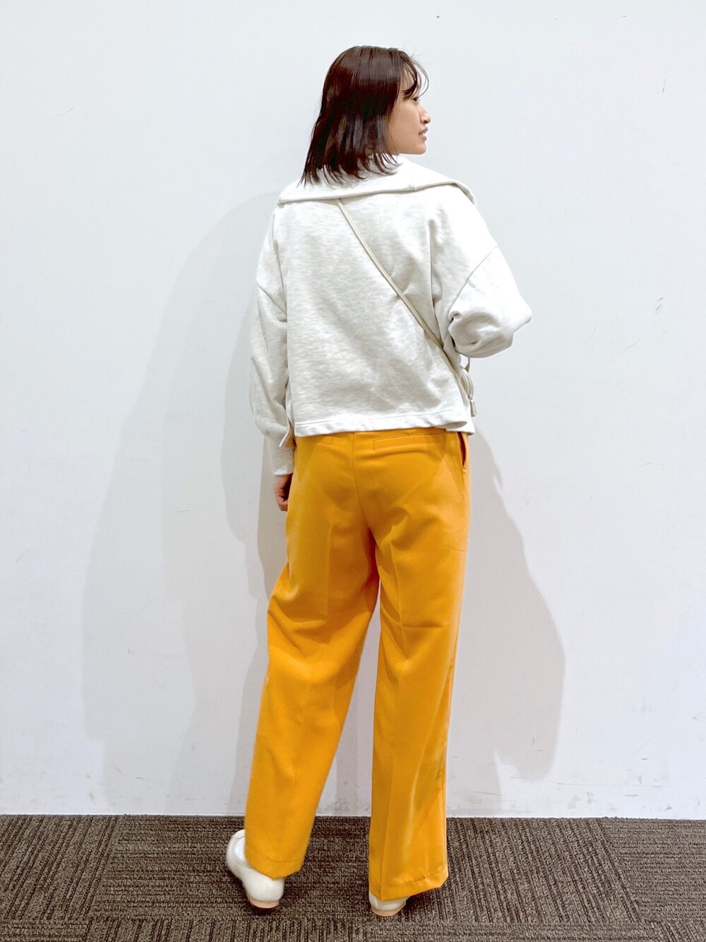 ホワイト系のバレエシューズ、オレンジ系のその他パンツ、ホワイト系のショルダーバッグを着用したレディースの冬コーディネートの3枚目の写真