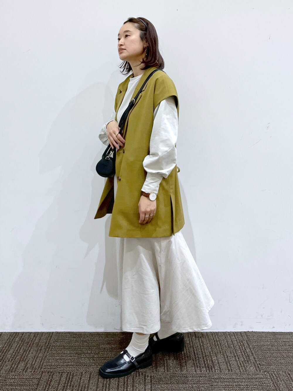 イエロー系のジャケット/アウター、ブラック系のショルダーバッグ、ホワイト系のワンピース/ドレスを着用したレディースの春コーディネートの2枚目の写真