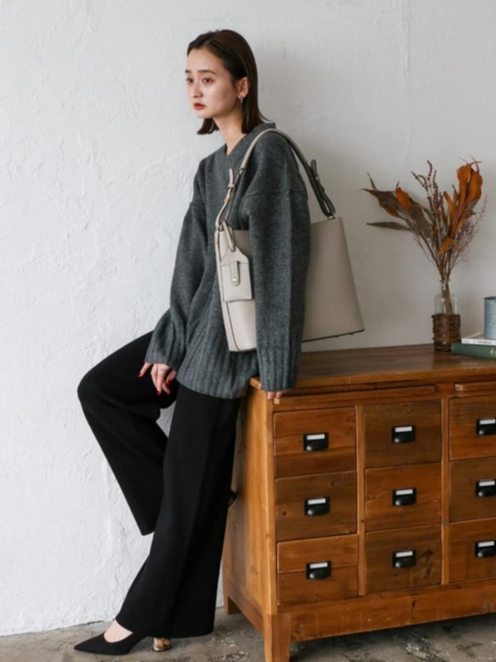 グレー系のニット/セーター、グレー系のトートバッグを着用したレディースの秋コーディネートの1枚目の写真