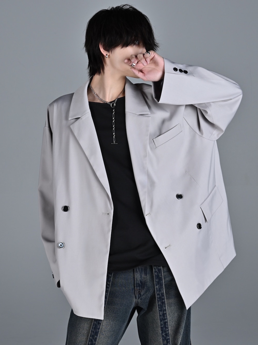 ブルー系のデニムパンツ、レッド系のタンクトップ、グレー系のテーラードジャケットを着用したメンズの冬コーディネートの1枚目の写真