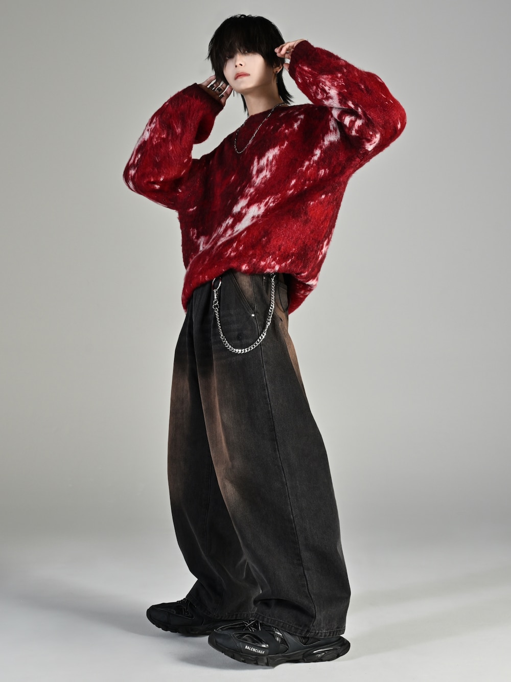 ブラック系のスニーカー、レッド系のニット/セーター、ブラック系のデニムパンツを着用したメンズの秋コーディネートの1枚目の写真