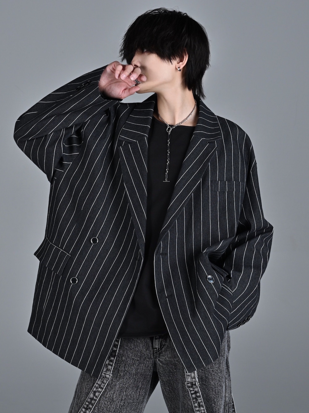 レッド系のタンクトップ、ブラック系のテーラードジャケット、ブラック系のデニムパンツを着用したメンズの冬コーディネートの1枚目の写真