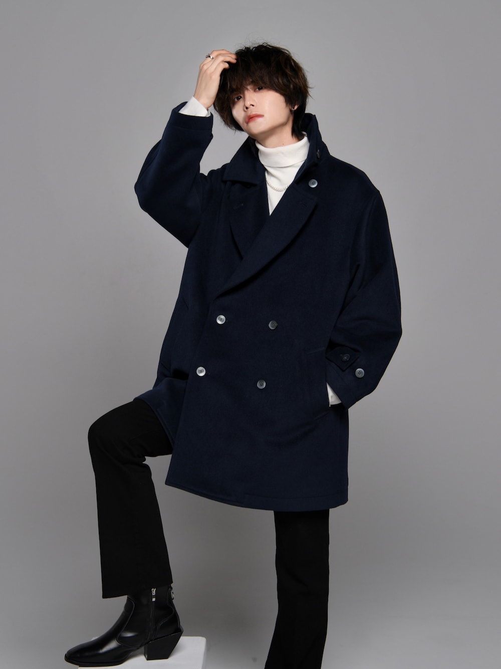 ブラック系のスラックス、ブラック系のブーツ、ホワイト系のニット/セーターを着用したメンズの秋コーディネートの1枚目の写真