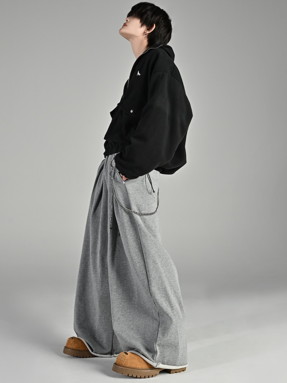 ベージュ系のブーツ、ブラック系のブルゾン、グレー系のスウェットパンツを着用したメンズの秋コーディネートの1枚目の写真