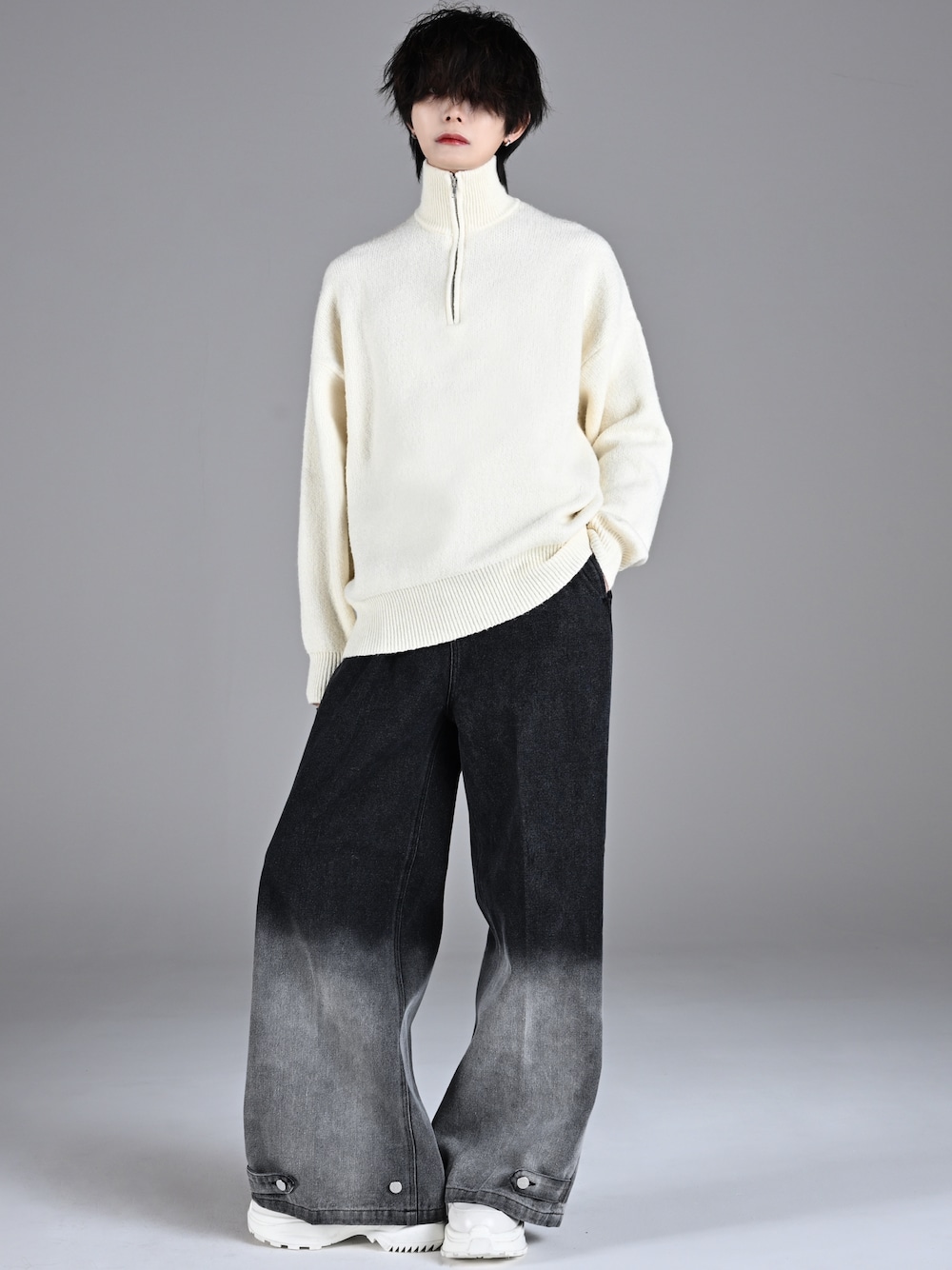 ホワイト系のスニーカー、ホワイト系のニット/セーター、ブラック系のデニムパンツを着用したメンズの秋コーディネートの1枚目の写真