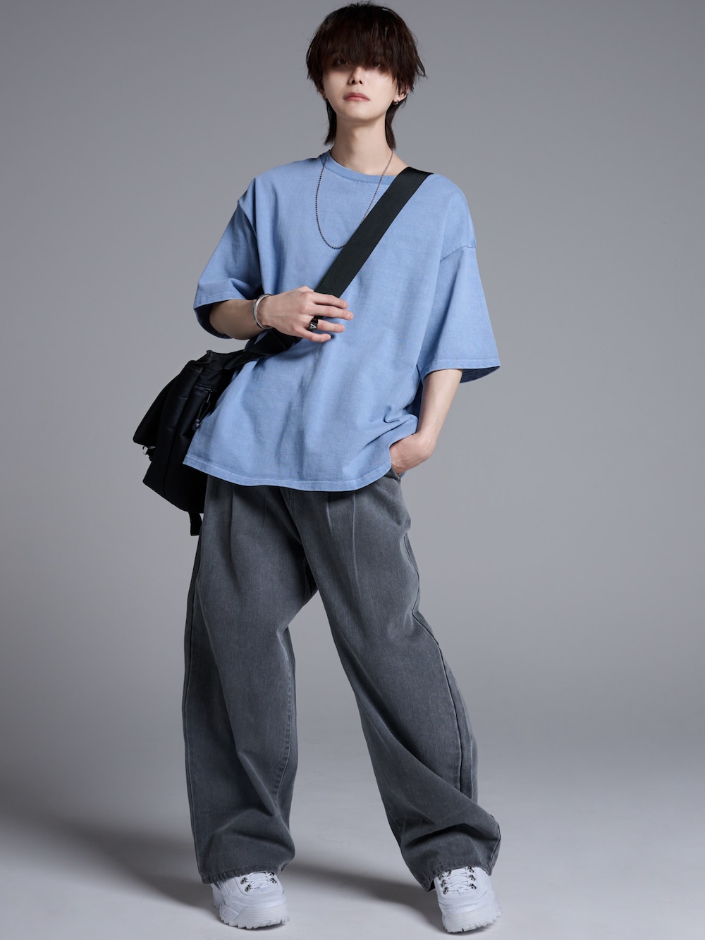 グレー系のデニムパンツ、ホワイト系のスニーカー、ブラック系のショルダーバッグを着用したメンズの春コーディネートの1枚目の写真