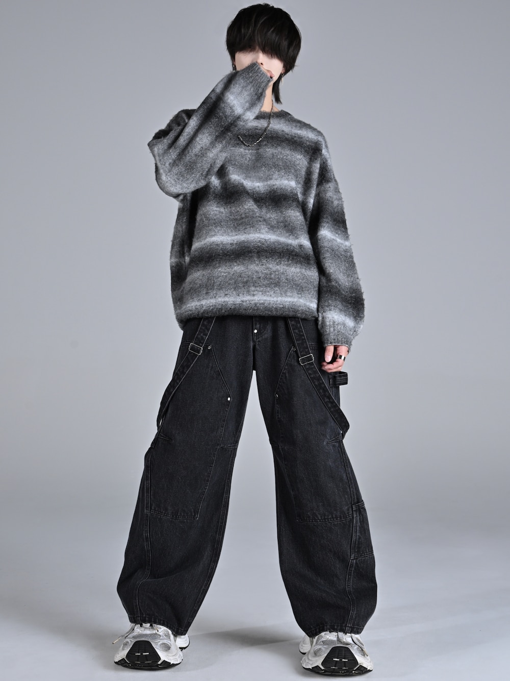 ブラック系のニット/セーター、ブラック系のデニムパンツ、ホワイト系のスニーカーを着用したメンズの秋コーディネートの1枚目の写真