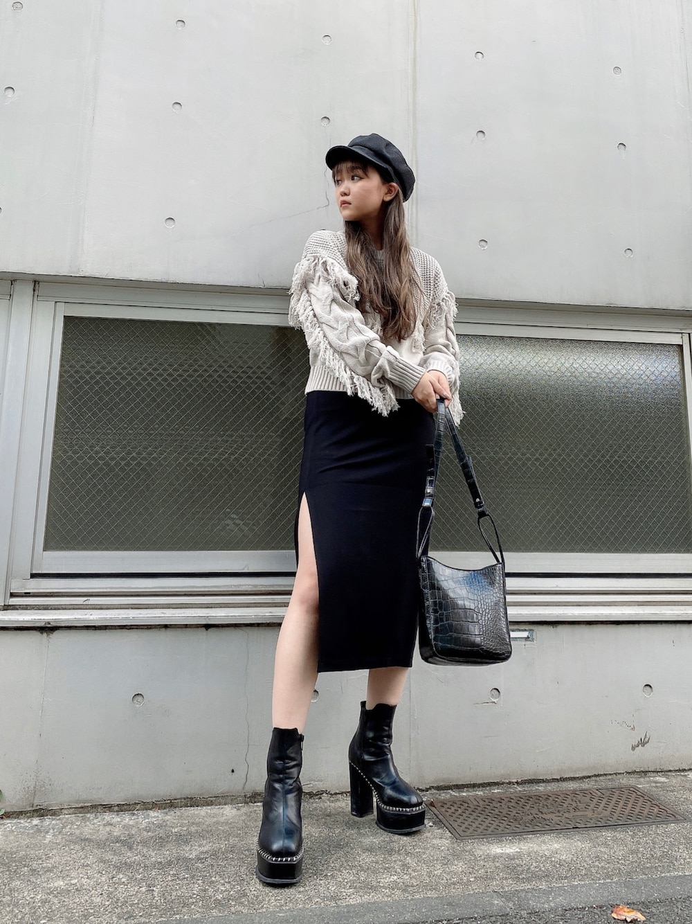 グレー系のニット/セーター、ブラック系のスカート、ブラック系のブーツを着用したレディースの秋コーディネートの1枚目の写真