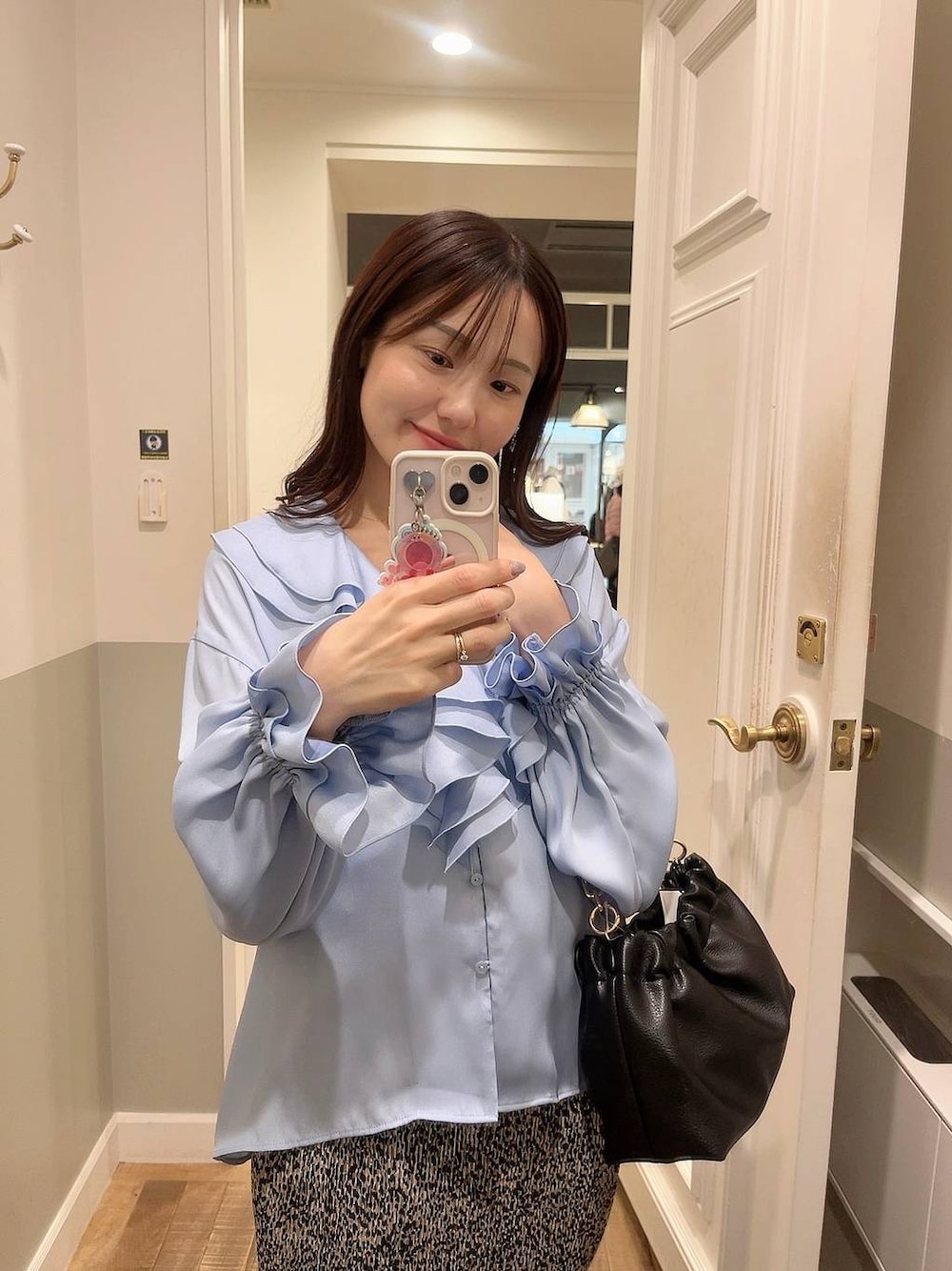 ベージュ系のスカート、ブラック系のショルダーバッグ、ホワイト系のキャミソールを着用したレディースの冬コーディネートの1枚目の写真