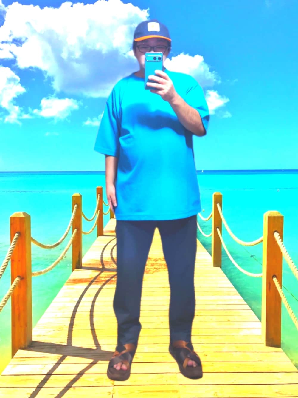 ブルー系のTシャツ/カットソー、グレー系のスラックス、ブルー系のキャップを着用したメンズの夏コーディネートの1枚目の写真