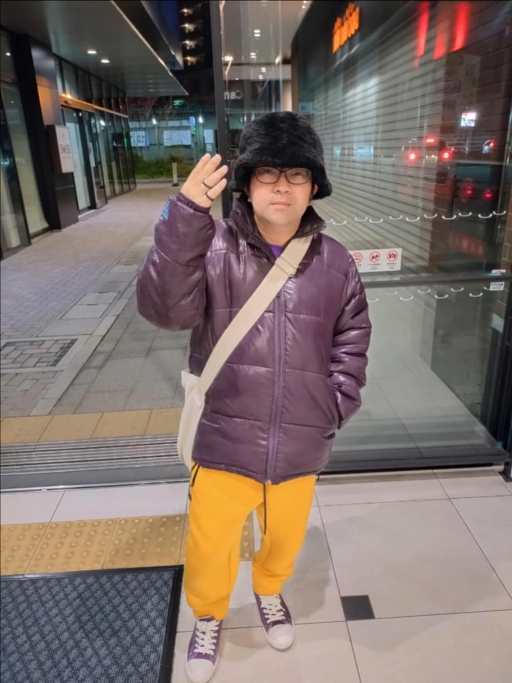 パープル系のダウンジャケット/コート、イエロー系のパンツ、パープル系のスニーカーを着用したメンズの冬コーディネートの1枚目の写真