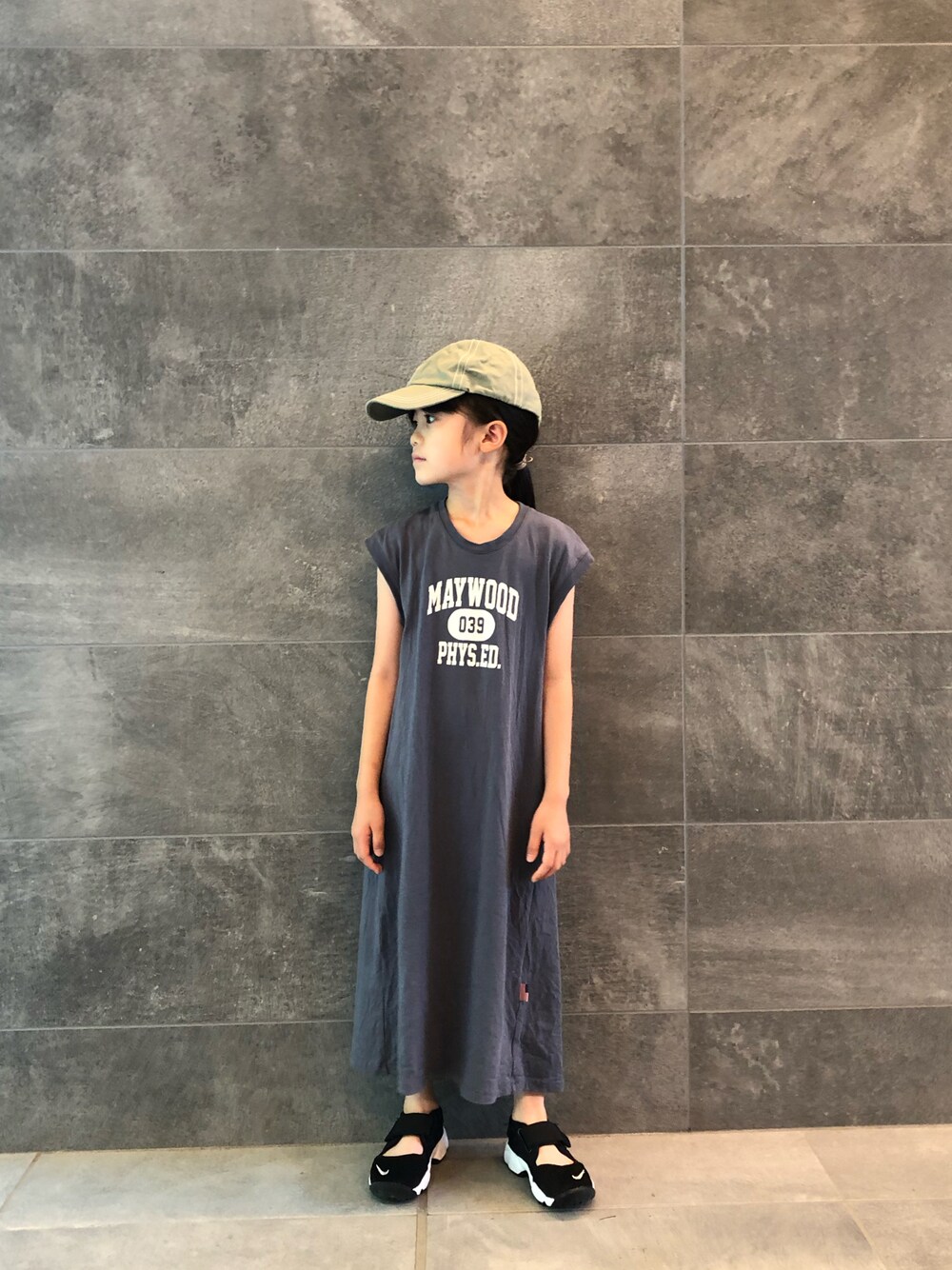 ブルー系のワンピース、ブラック系のスニーカー、グリーン系のキャップを着用したキッズの夏コーディネートの1枚目の写真