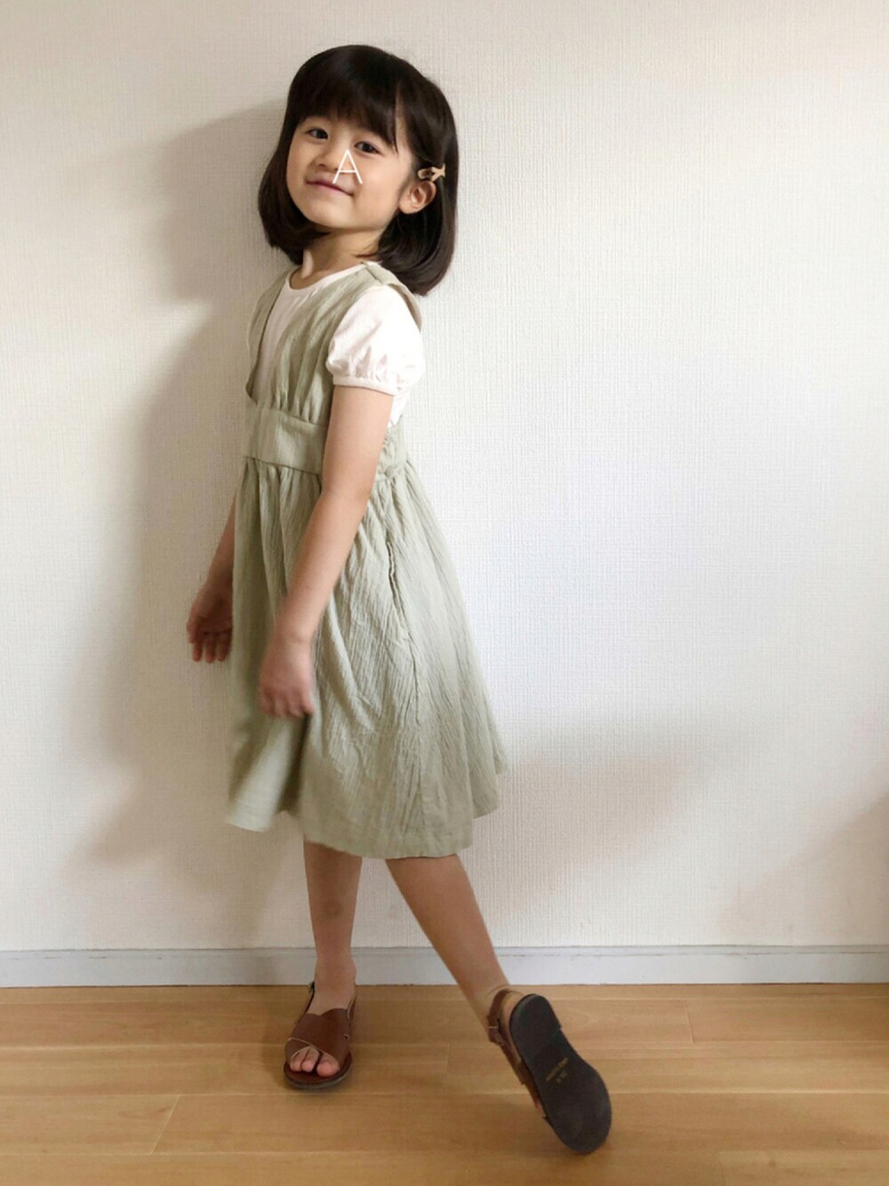 グリーン系のワンピース、ブラウン系のサンダル、グリーン系のラッピングキットを着用したキッズの夏コーディネートの1枚目の写真