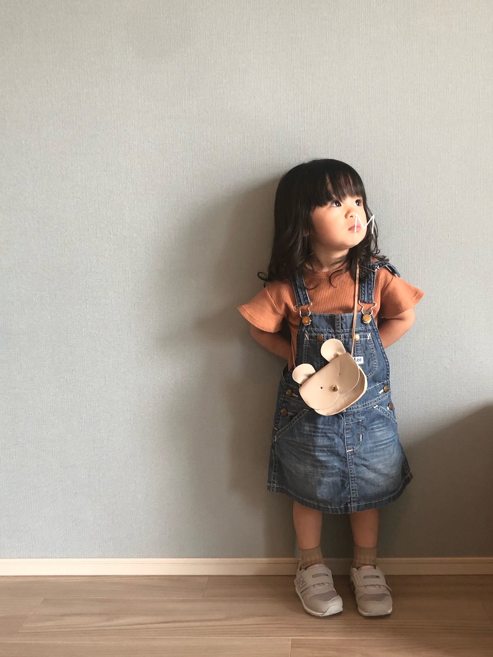 ブラウン系のトップス、ブルー系のサロペット/オーバーオール、ベージュ系のショルダーバッグを着用したキッズの秋コーディネートの1枚目の写真