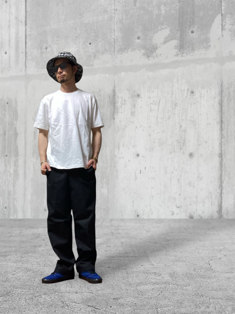 ブラック系のチノパンツ、ブルー系のスニーカー、ホワイト系のTシャツ/カットソーを着用したメンズの秋コーディネートの1枚目の写真
