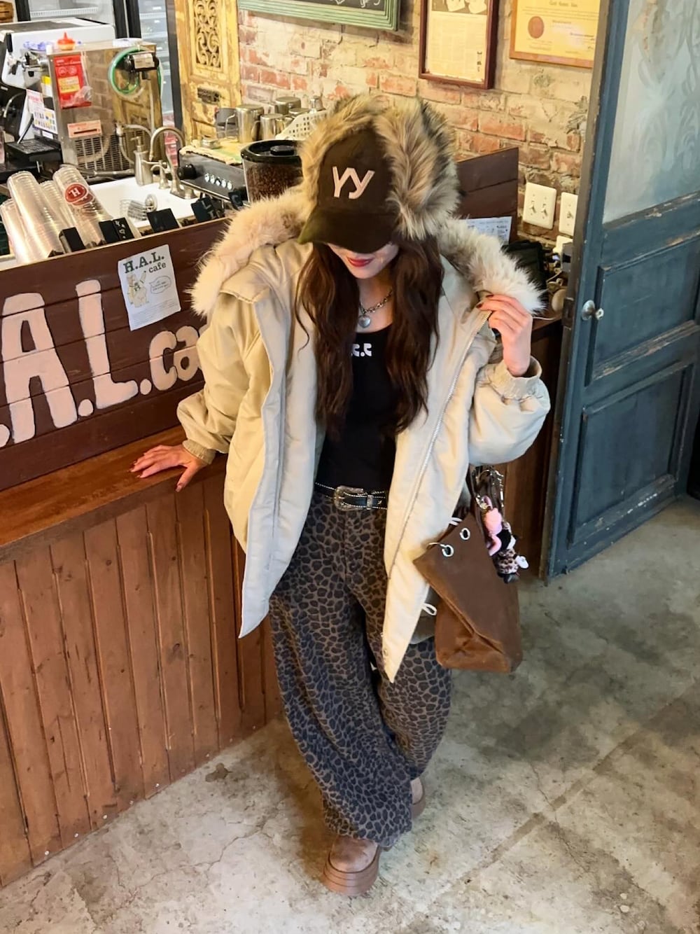 ホワイト系のブルゾン、ブラック系のTシャツ/カットソー、ブラウン系のパンツを着用したレディースの秋コーディネートの1枚目の写真