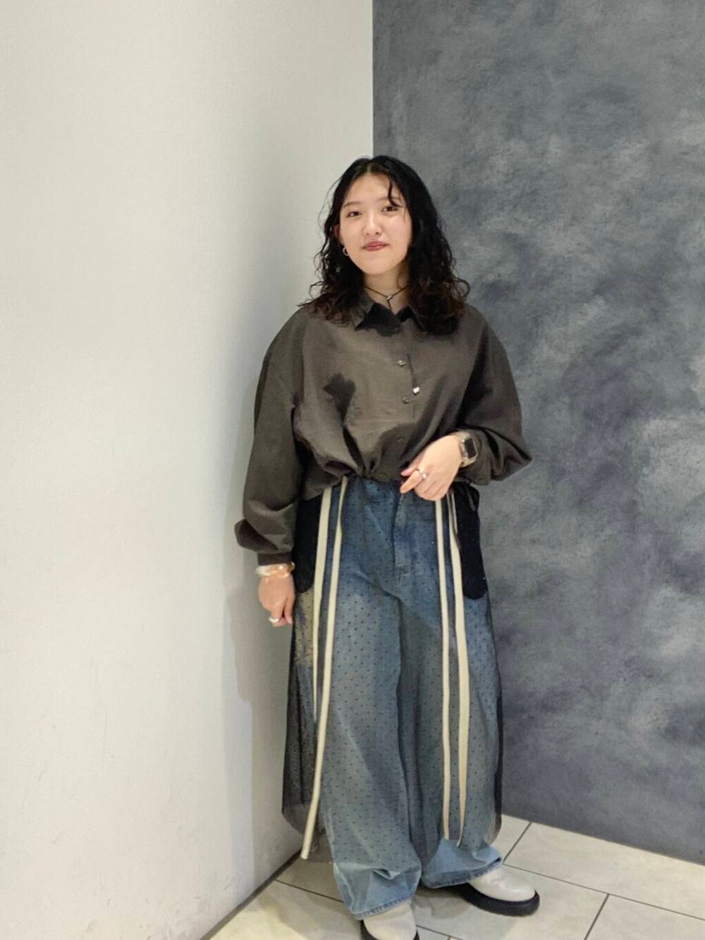ブルー系のデニムパンツ、ブラウン系のシャツ/ブラウス、ブラック系のスカートを着用したレディースの秋コーディネートの1枚目の写真