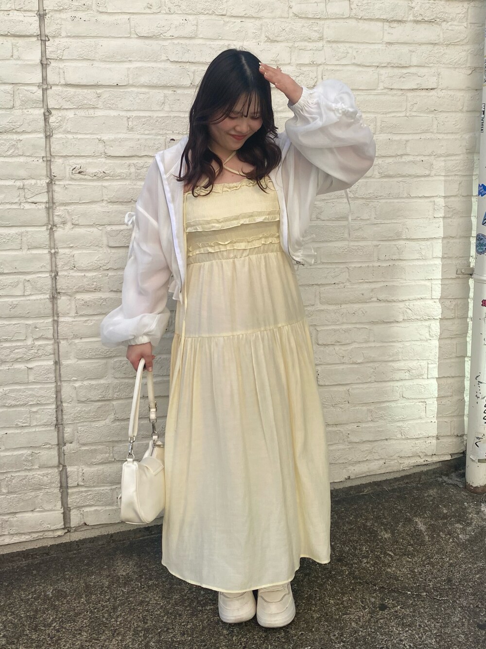 イエロー系のワンピース、ホワイト系のブルゾン、ホワイト系のショルダーバッグを着用したレディースの春コーディネートの1枚目の写真