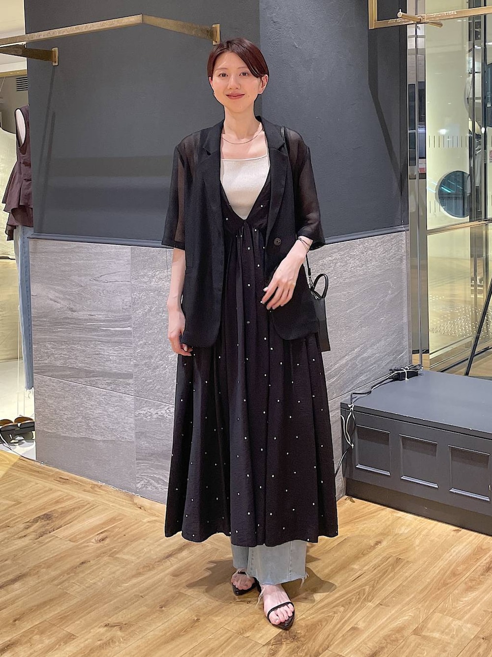 ブラック系のワンピース、ブルー系のデニムパンツ、ブラック系のサンダルを着用したレディースの夏コーディネートの1枚目の写真